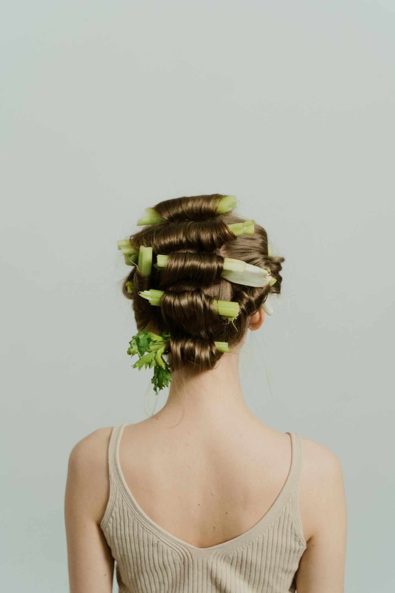 Unique hairstyle concept featuring celery and organic vegetables in brunette hair.